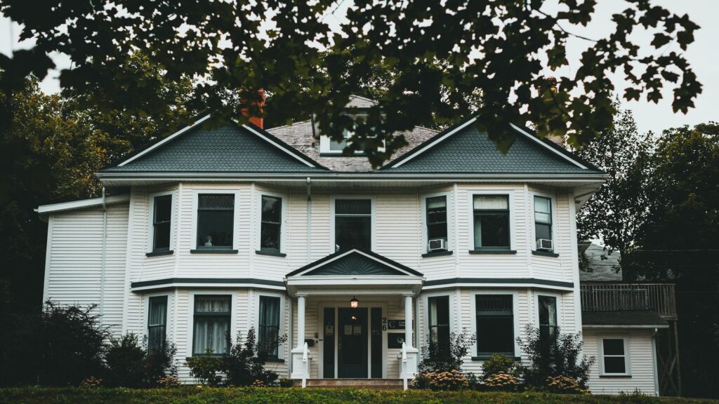 Victorian-style house exterior with a lush front yard, showcasing classic residential architecture.