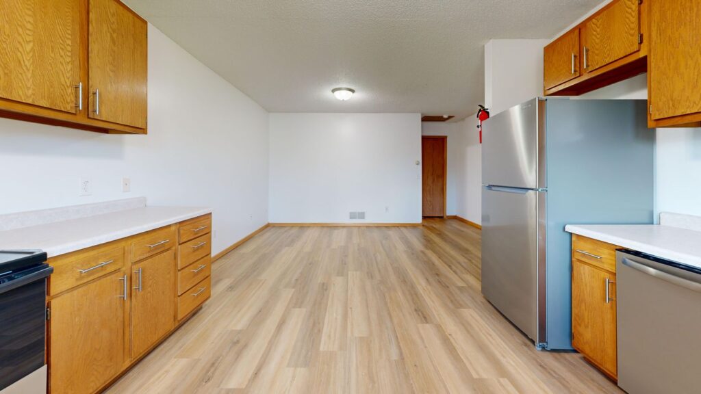 Empty modern kitchen interior with wooden cabinets and fridge.