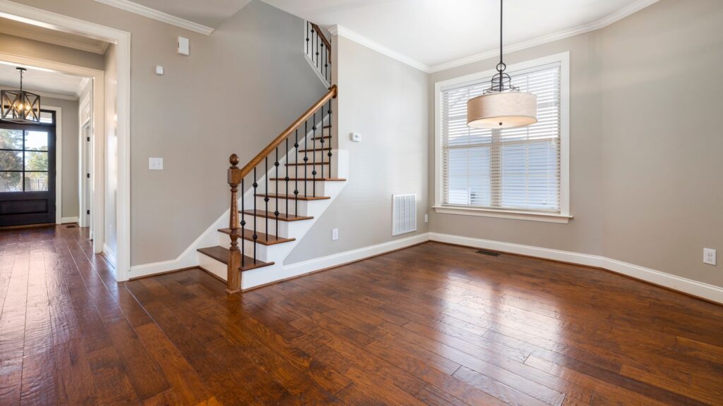 Bright and airy room with wooden floors and staircase, ideal for modern living.