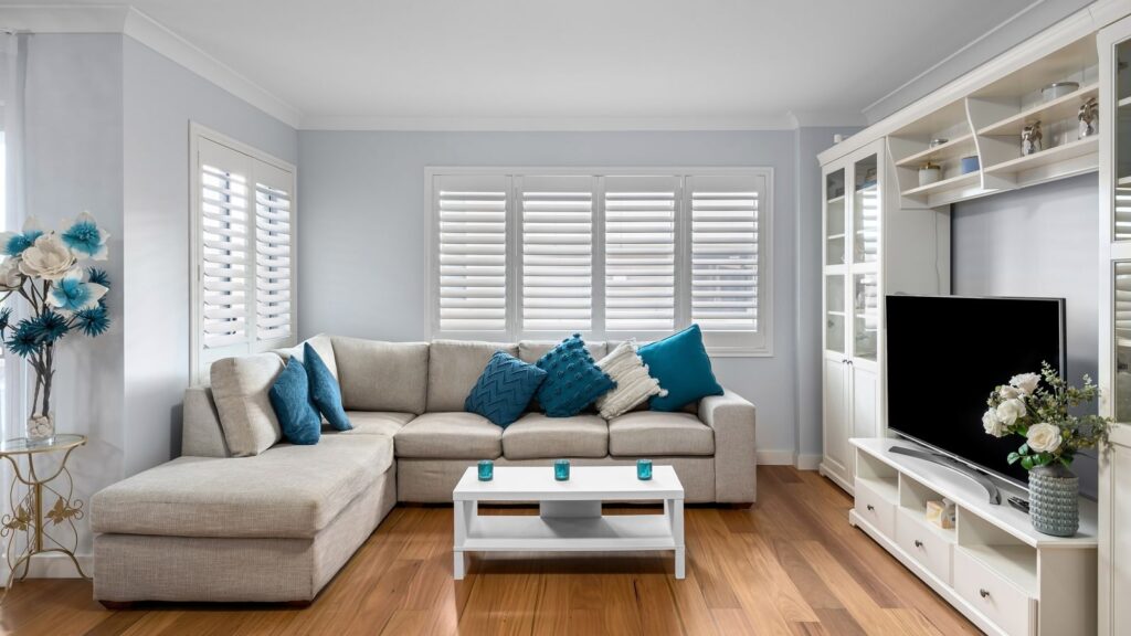 Elegant living room featuring a gray sofa, blue accents, and a flat screen TV.