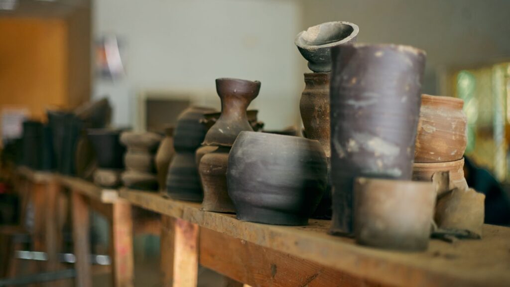 A collection of rustic pottery displayed on a wooden shelf, capturing the artisanal charm of handmade ceramics.